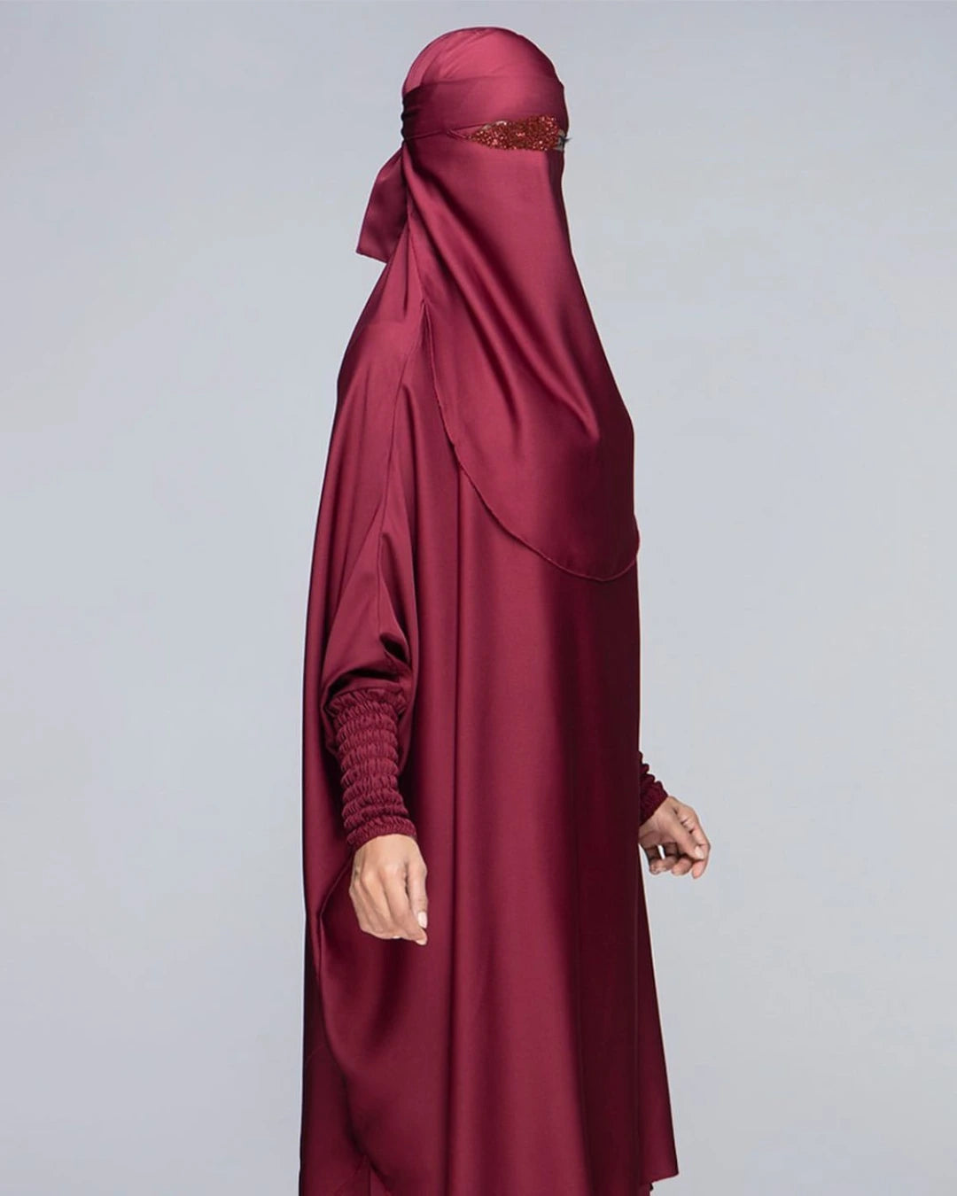 Detaillierte Ansicht des 3-teiligen Jilbab-Set in Bordeaux von der Seite mit weitem Khimar, Rock, Niqab und detailreichen, strukturierten Ärmelbündchen. In Einheitsgröße passend für kleine und große Frauen.