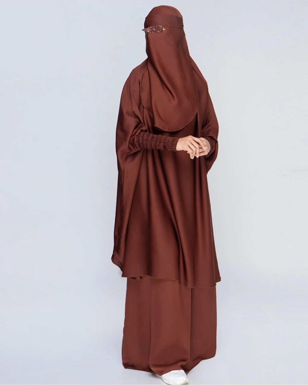 Detaillierte Ansicht des 3-teiligen Jilbab-Set in Schokobraun von der Seite mit weitem Khimar, Rock, Niqab und detailreichen, strukturierten Ärmelbündchen. In Einheitsgröße passend für kleine und große Frauen. 